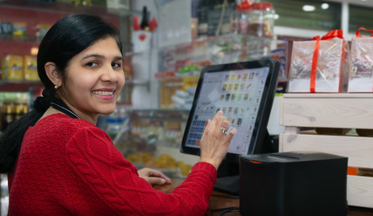A woman smiles while using a POS machine | Condor PH