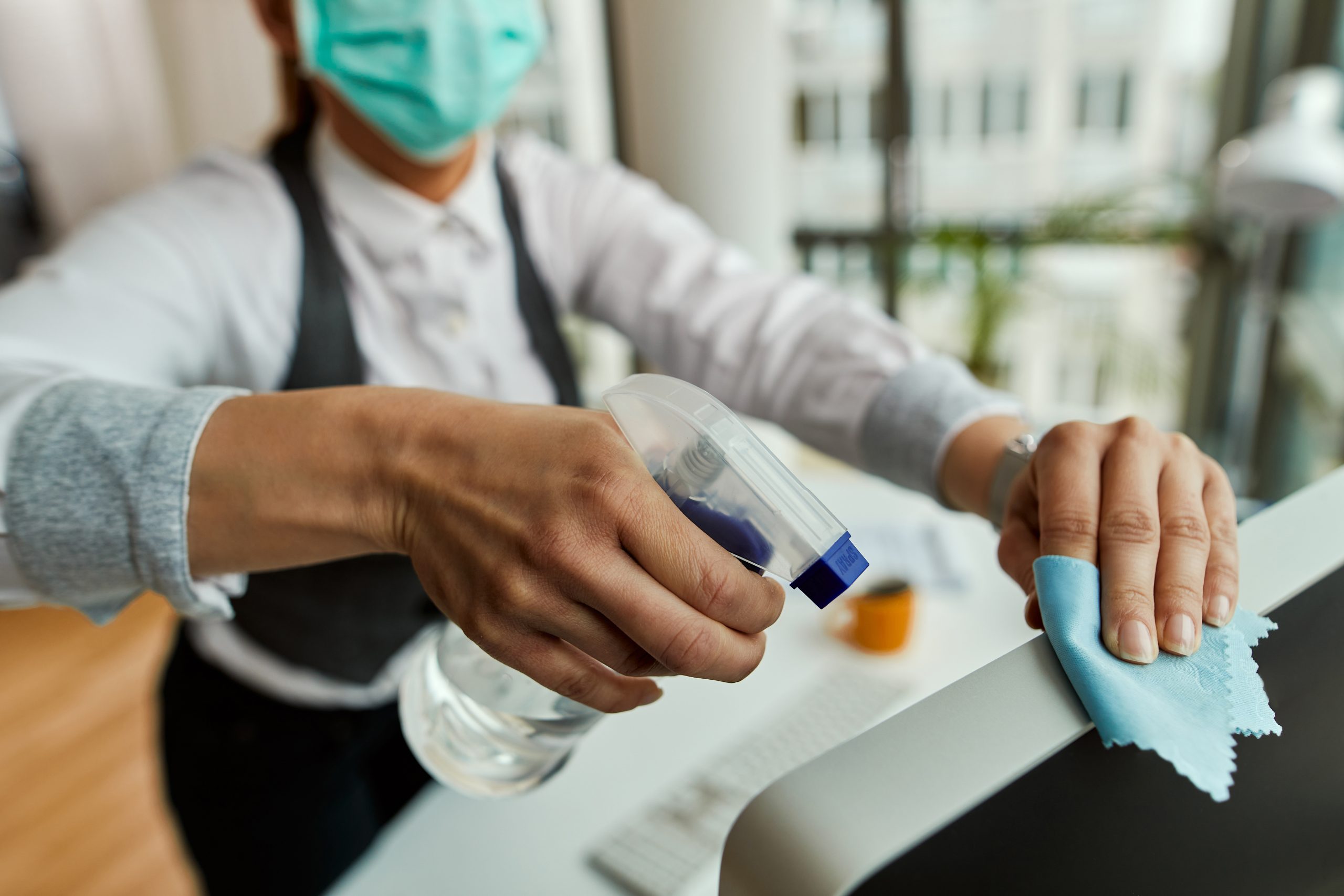 Close-up of businesswoman disinfecting her desktop PC in the office. Woman Cleaning a Computer Monitor with Microfiber Cloth and Screen-Safe Spray | Condor PH
