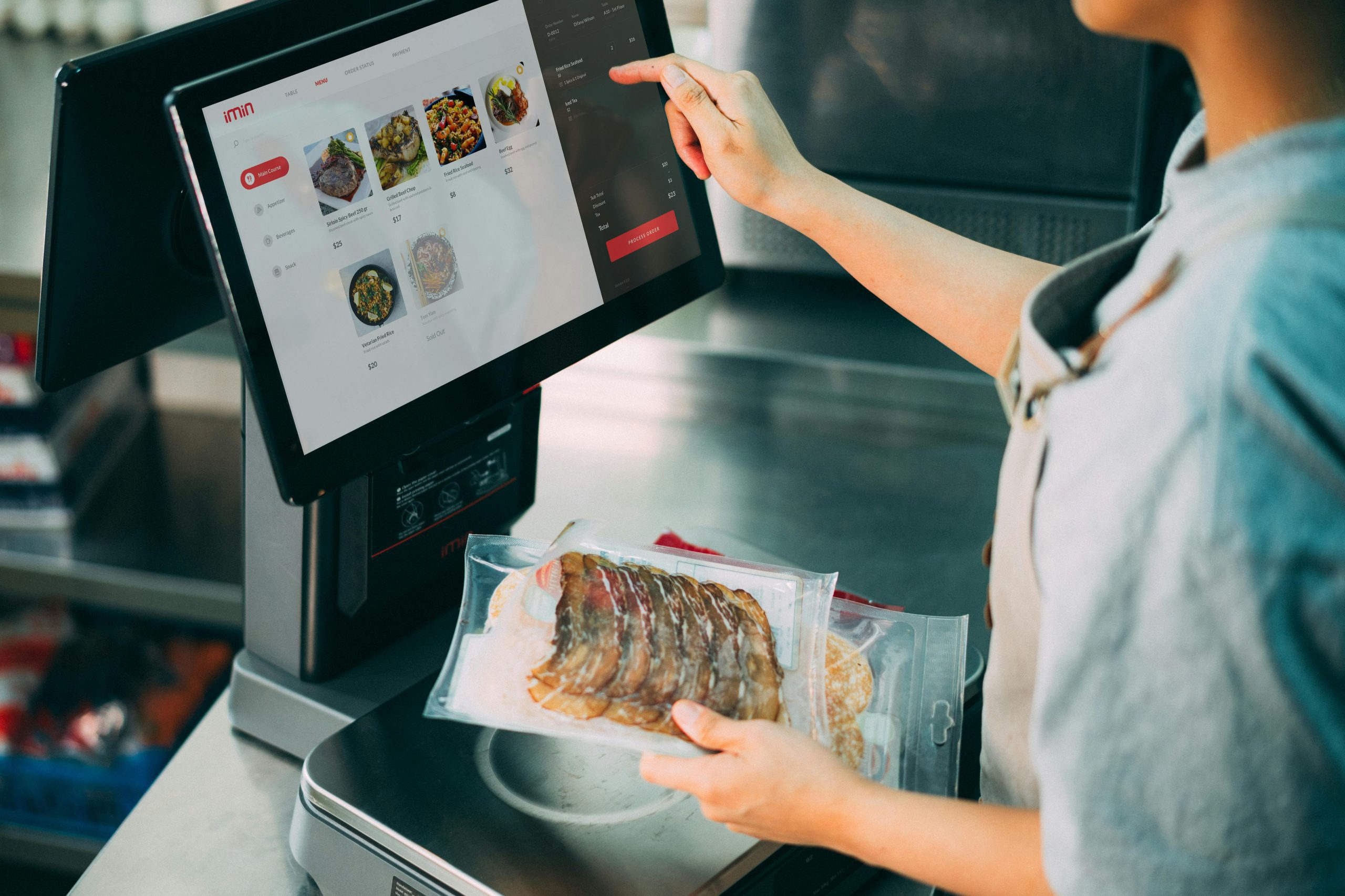 A Food Service Worker Using a Touch Screen POS Monitor While Holding Packaged Goods | Condor PH A Food Service Worker Using a Touch Screen POS Monitor While Holding Packaged Goods | Condor PH