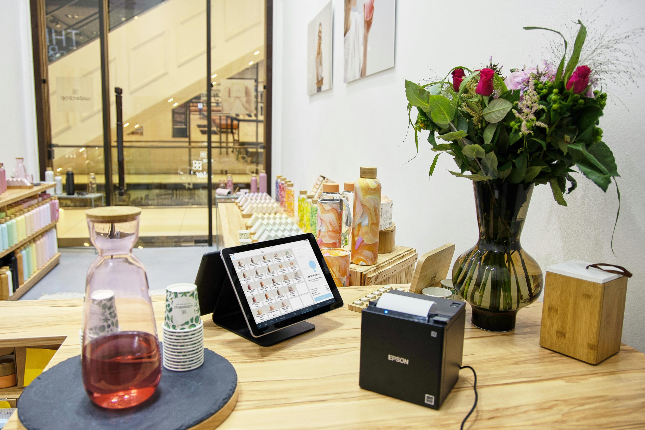 A Touch Screen POS Monitor and Receipt Printer Setup on a Wooden Counter in a Lifestyle Retail Store A Touch Screen POS Monitor and Receipt Printer Setup on a Wooden Counter in a Lifestyle Retail Store