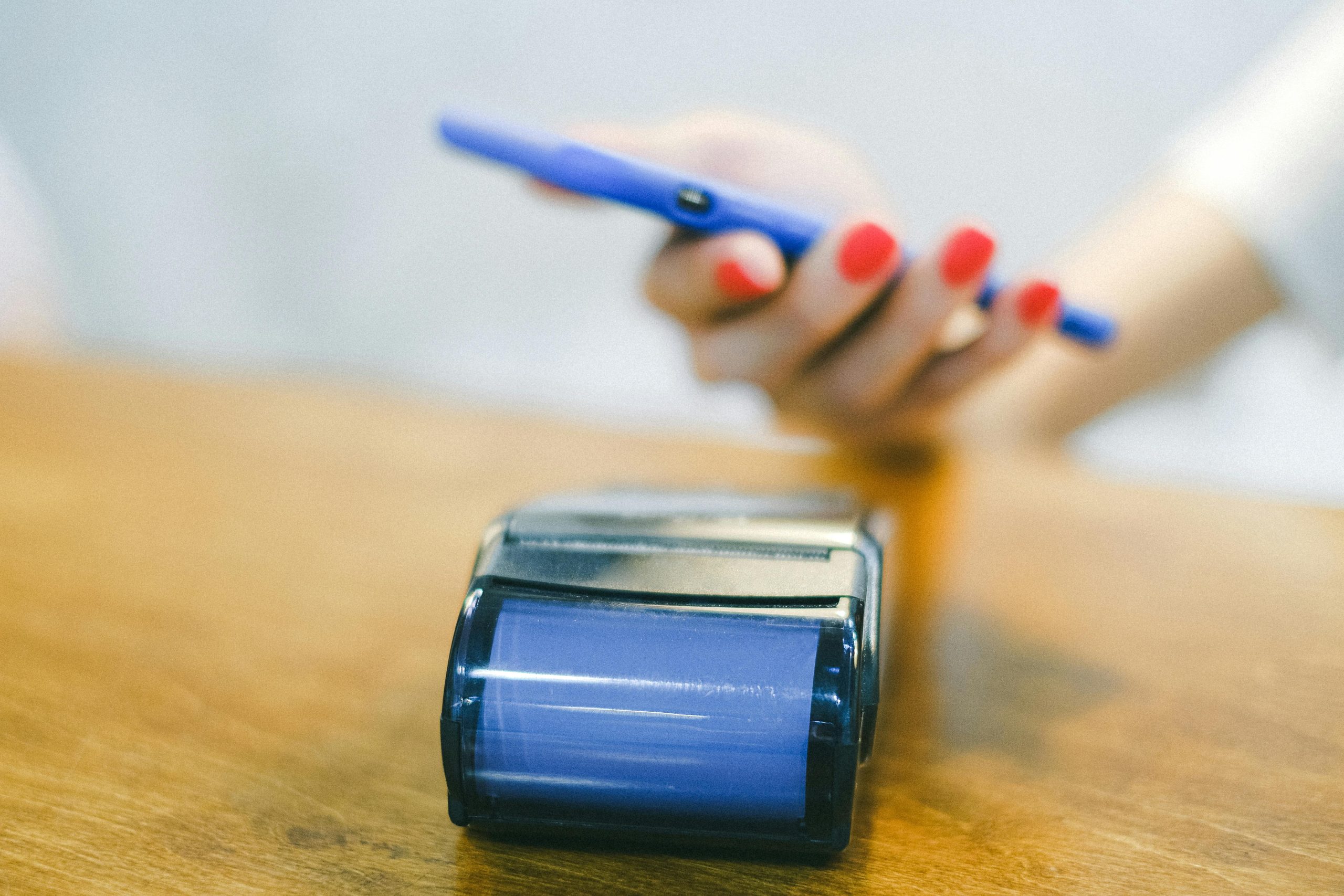 A Woman Holding a Smartphone Over a Mobile Receipt Printer for Wireless Payment