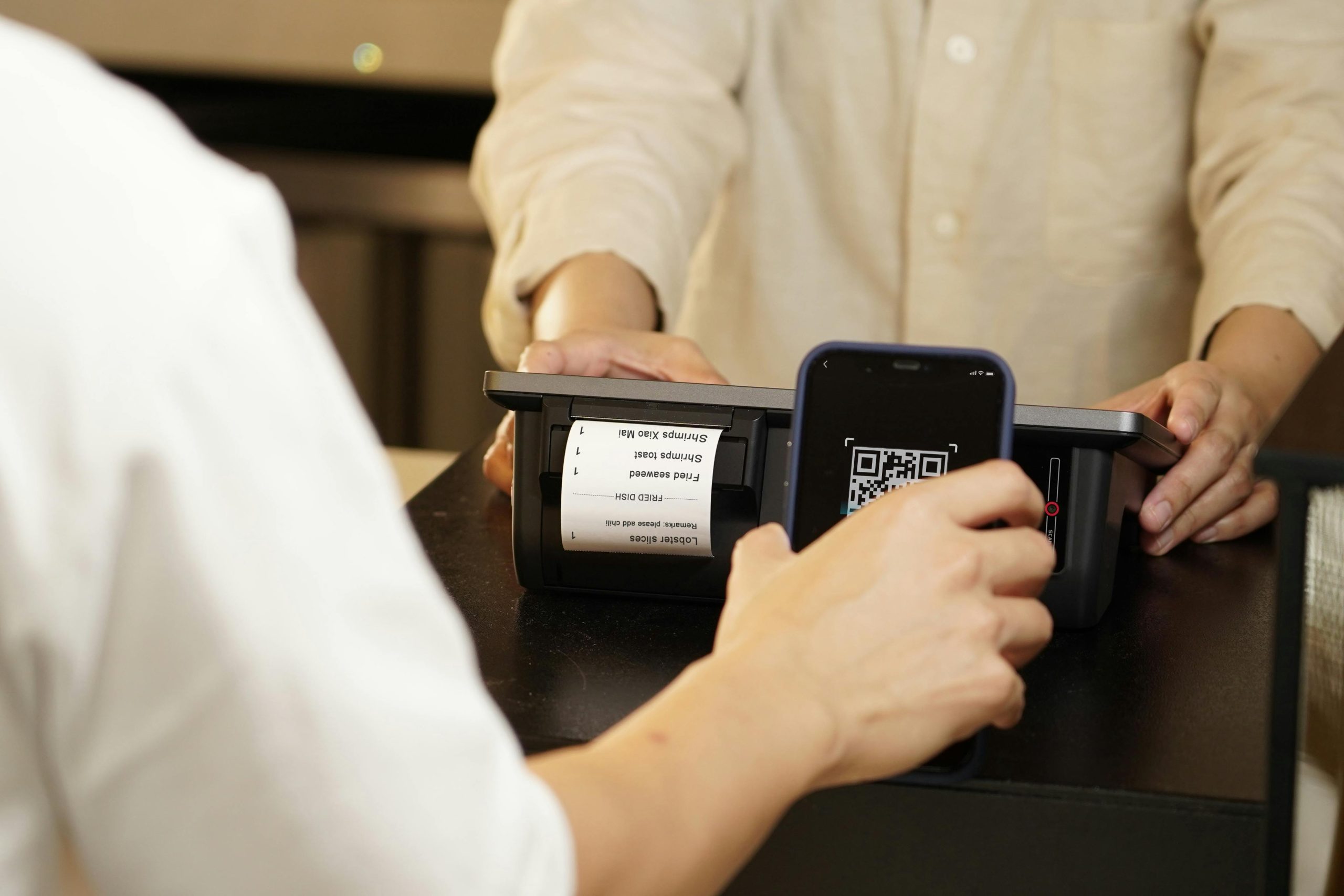 Customer Scanning a QR Code with a Smartphone at a POS Terminal