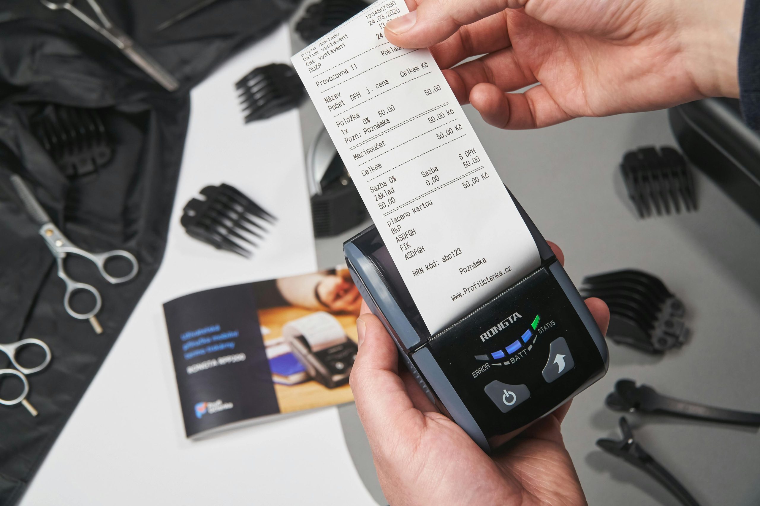 A close-up of a hand holding a printed receipt from a mobile POS thermal printer in a grooming or barbershop setup | Condor PH