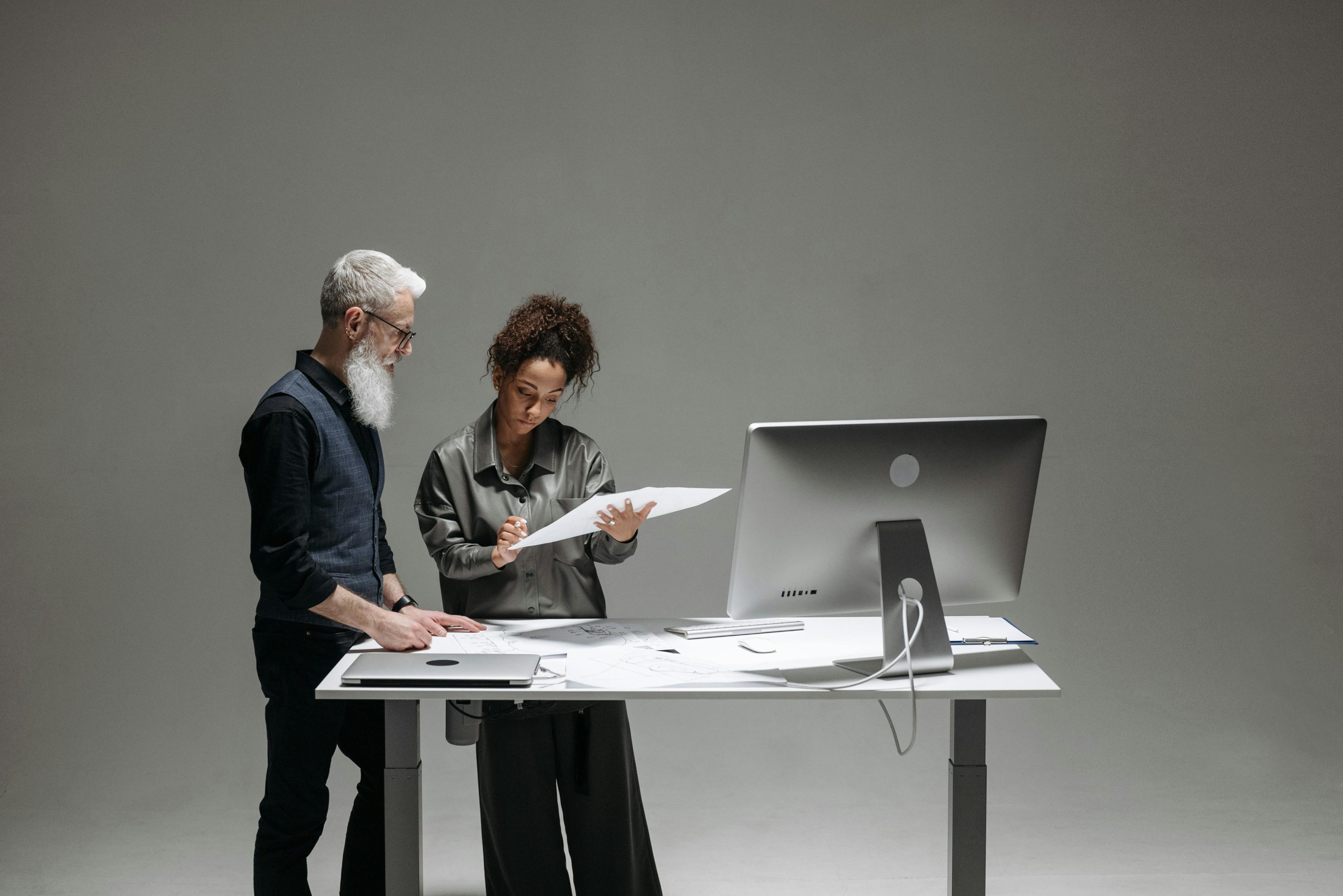 Two Professionals Discussing Documents at a Standing Desk with a Modern Computer Monitor | Condor PH